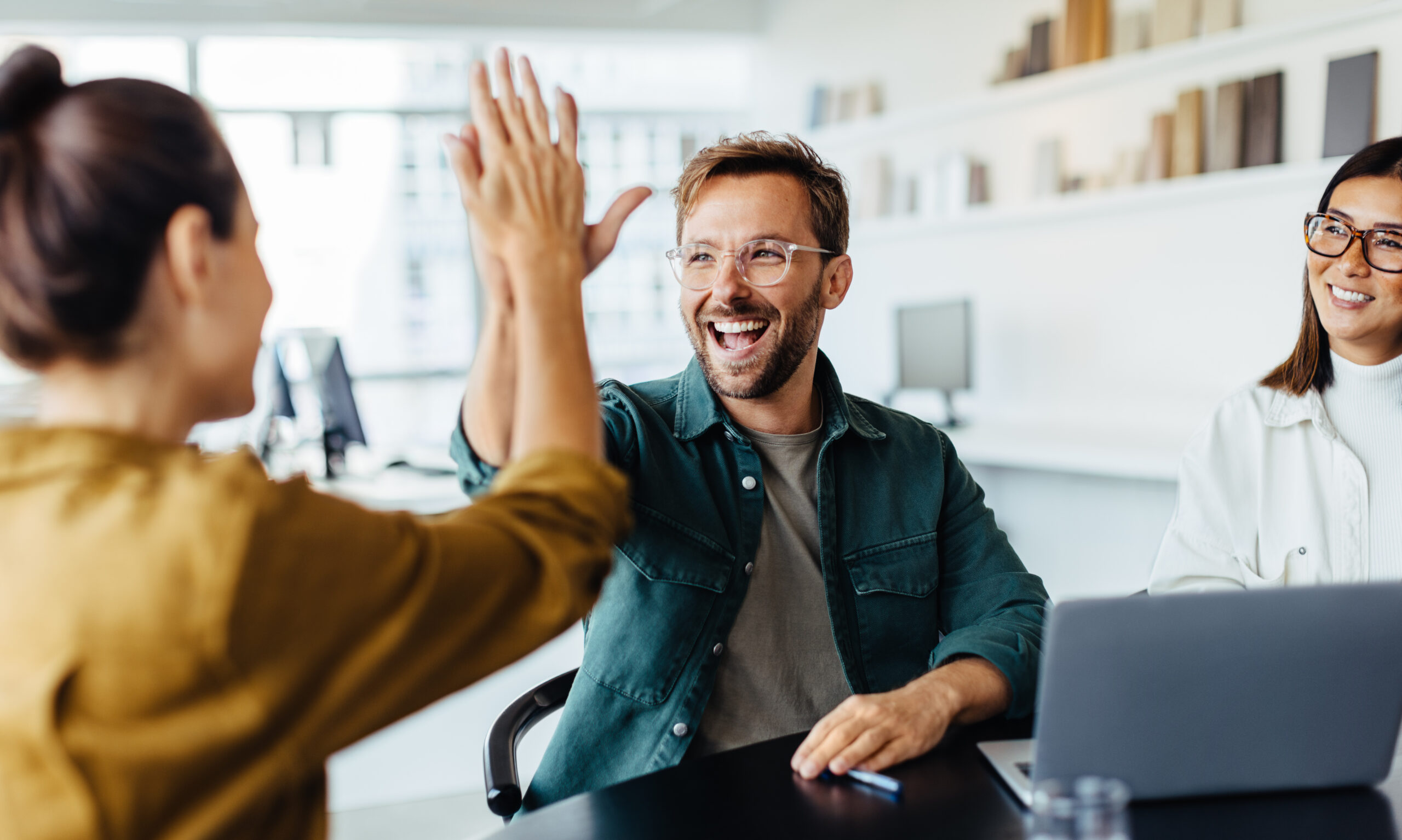 Successful team members giving each other a high five in an office meeting.