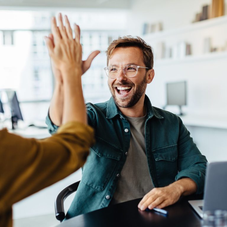 Successful team members giving each other a high five in an office meeting.